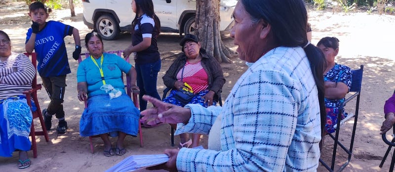 a woman holding papers explaining to other women who are sitting listening